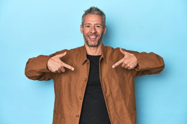 Mavi zemin üzerinde orta yaşlı beyaz bir adam parmağını göstererek şaşırdı ve gülümsedi..