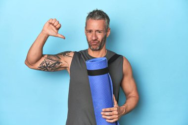 Mavi bir stüdyo arka planında paspası olan sporcu gururlu ve kendinden emin hissediyor, örnek olarak.