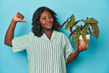 Stüdyoda bitki tutan kıvrımlı bahçıvan gururlu ve kendinden emin hissediyor, örnek olarak.