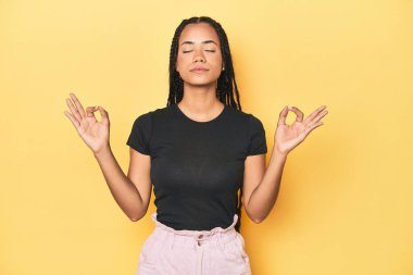 Sarı stüdyodaki genç Endonezyalı kadın çalışkan bir günün ardından rahatlıyor. Yoga yapıyor..