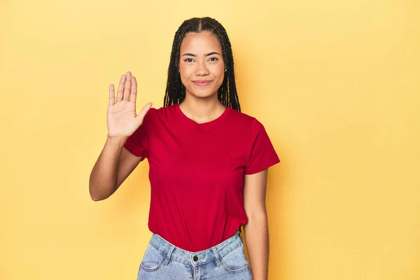 黄色いスタジオの若いインドネシアの女性 バックドロップ笑顔 指でナンバーを示しています — ストック写真