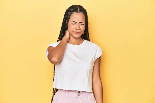 ストレス マッサージ 手触りによる首の痛みを持つ黄色いスタジオバックドロップの若いインドネシアの女性 — ストック写真
