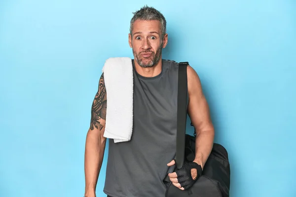 Athlete Gym Backpack Blue Background Shrugs Shoulders Open Eyes Confused — Stock Photo, Image