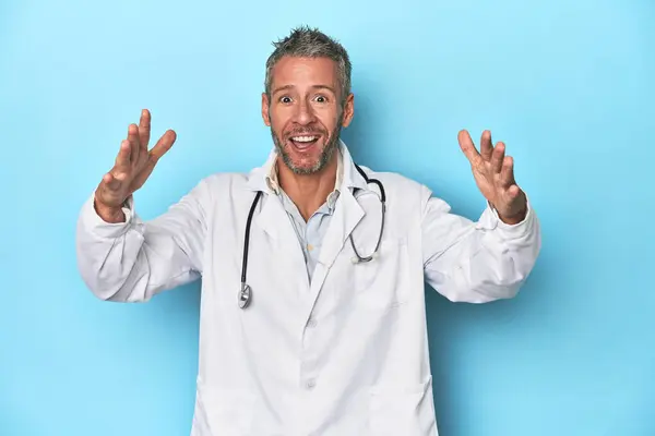 Caucasian Middle Aged Doctor Blue Background Receiving Pleasant Surprise Excited — Stock Photo, Image
