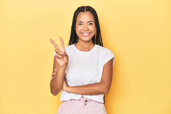 黄色いスタジオのバックドロップの若いインドネシアの女性は指でナンバー2を示しています — ストック写真