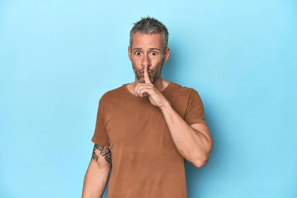 stock image Middle-aged caucasian man on blue backdrop keeping a secret or asking for silence.