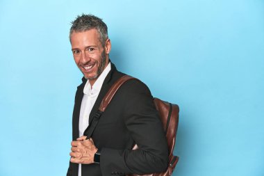 Mavi stüdyo arka planında sırt çantası olan bir iş adamı.