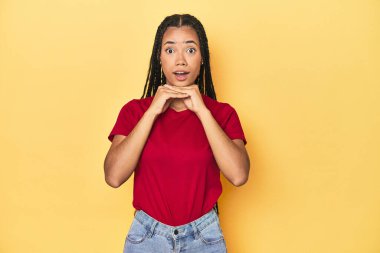 Sarı stüdyo stüdyosundaki genç Endonezyalı kadın şans için dua ediyor, şaşırıyor ve ağzını açıyor..