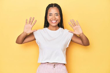 Sarı stüdyodaki genç Endonezyalı kadın 10 numarayı elleriyle gösteriyor..