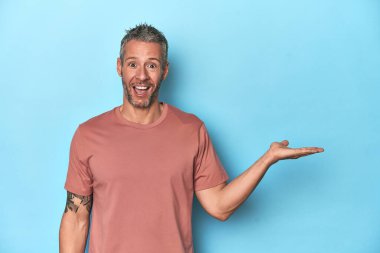 Mavi arka planda oturan orta yaşlı beyaz adam, avuç içi fotokopi alanını elinde tutmaktan çok etkilendi..