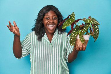 Kıvrımlı bahçıvan stüdyoda bitki tutuyor. Hoş bir sürpriz bekliyor, heyecanlı ve el kaldırıyor..