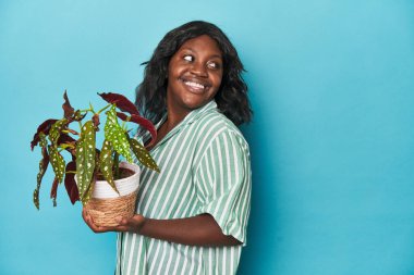 Stüdyoda çiçek tutan kıvrımlı bahçıvan gülümseyen, neşeli ve hoş bir tarafa bakıyor..