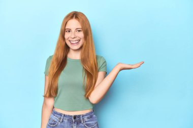 Mavi arka planda kızıl saçlı genç bir kadın avuç içinde fotokopi odası ve belinde bir el daha gösteriyor..