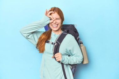 Stüdyoda sırt çantası ve paspas taşıyan kızıl saçlı gezgin..