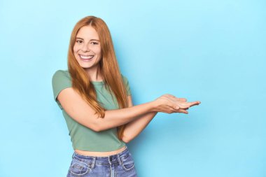 Mavi arka planda kızıl saçlı genç bir kadın avucunun içinde bir kopya alanı tutuyor..