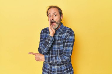 Sarı stüdyodaki orta yaşlı beyaz adam dedikodu yapıyor, bir şeyleri haber veriyor..