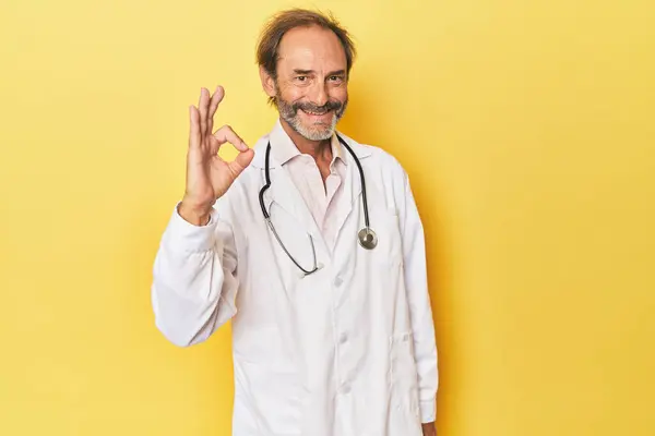 Lekarz Stetoskopem Żółtym Studio Wesoły Pewny Siebie Pokazując Gest — Zdjęcie stockowe