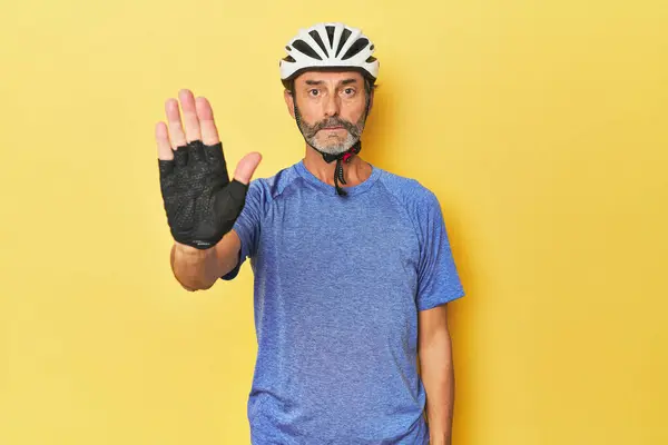 Cyclist Wearing Helmet Yellow Studio Standing Outstretched Hand Showing Stop — Stock Photo, Image
