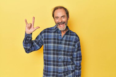 Sarı stüdyodaki orta yaşlı beyaz adam boynuzlarını devrim konsepti olarak gösteriyor..