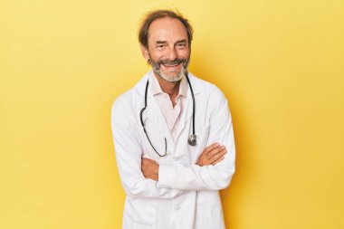Sarı stüdyoda steteskoplu bir doktor gülüyor ve eğleniyor..