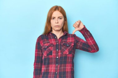 Mavi arka plandaki kızıl saçlı genç kadın hoşlanmadığı bir hareket gösteriyor. Anlaşmazlık konsepti.