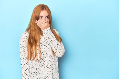 Mavi arka planda kızıl saçlı genç bir kadın. Bir fotokopi odasına dikkatlice bakıyor. Ağzını eliyle kapatıyor..