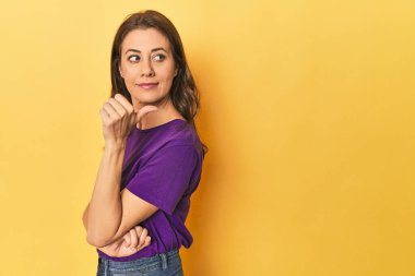 Yetişkin kadın portresi başparmağıyla işaret ediyor, gülüyor ve tasasız..