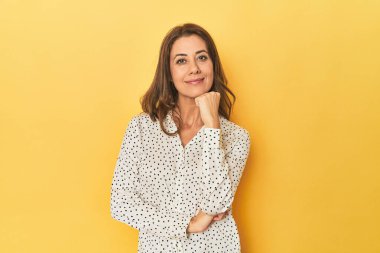 Gülümseyen mutlu ve kendinden emin güzel bir kadının portresi, elleriyle çeneye dokunuyor..