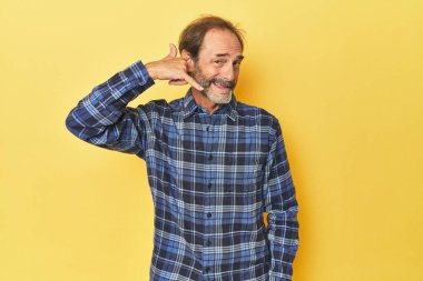 Sarı stüdyodaki orta yaşlı beyaz adam cep telefonu hareketini parmaklarıyla gösteriyor..