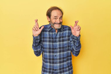 Sarı stüdyoda orta yaşlı bir adam şans diliyor.