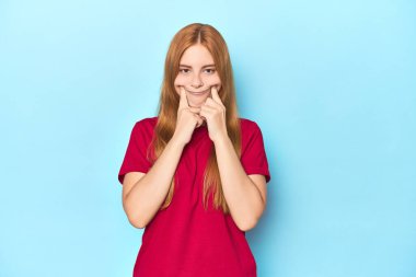 Mavi arka plandaki kızıl saçlı genç kadın iki seçenek arasında şüpheye düşüyor.