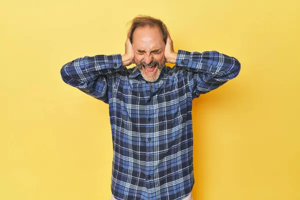 Caucasian Middle Aged Man Yellow Studio Covering Ears Hands Trying — Stock Photo, Image
