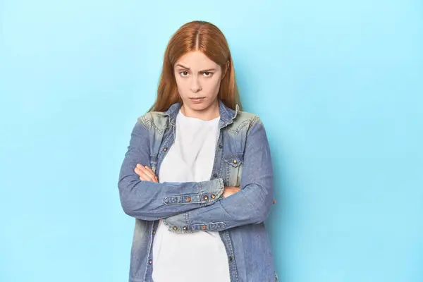 Rothaarige Junge Frau Auf Blauem Hintergrund Blickt Mit Sarkastischem Gesichtsausdruck — Stockfoto