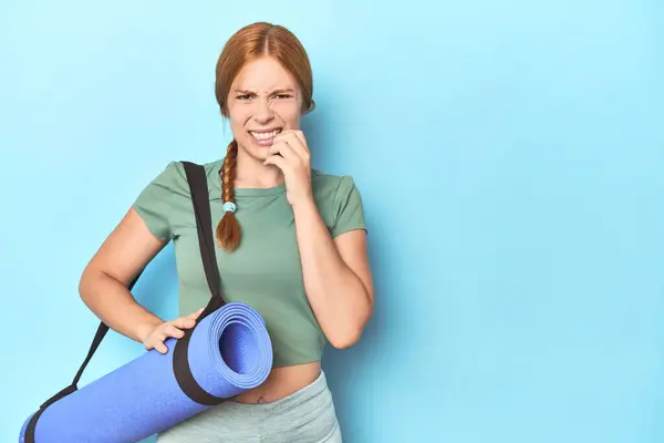 Kızıl Saçlı Genç Kadın Stüdyoda Yoga Minderi Tutuyor Tırnaklarını Yiyor — Stok fotoğraf