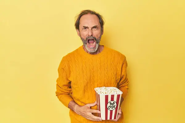 Mężczyzna Korzystających Popcorn Żółtym Studio Krzyczy Bardzo Zły Agresywny — Zdjęcie stockowe