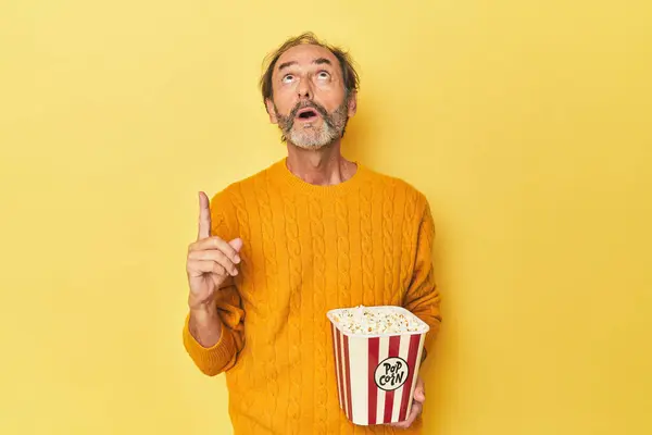 Man Enjoying Popcorn Yellow Studio Pointing Upside Opened Mouth — Stock Photo, Image