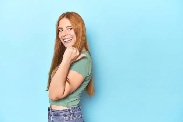 Roodharige Jonge Vrouw Blauwe Achtergrond Punten Met Duim Vinger Weg — Stockfoto