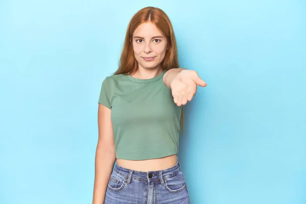 Roodharige Jonge Vrouw Blauwe Achtergrond Stretching Hand Camera Groet Gebaar — Stockfoto
