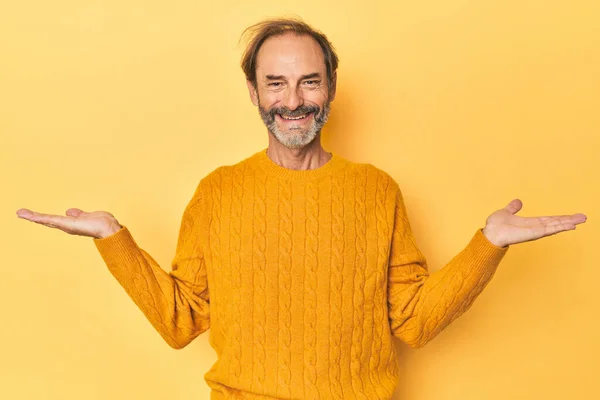 黄色いスタジオで管理する白人中年の男性は腕でスケールを作り 幸せで自信を持って感じます — ストック写真
