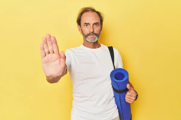 Man Yoga Mat Yellow Studio Standing Outstretched Hand Showing Stop — Stock Photo, Image
