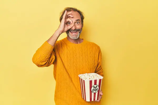 Mężczyzna Korzystających Popcorn Żółty Studio Podekscytowany Utrzymanie Gest Oko — Zdjęcie stockowe