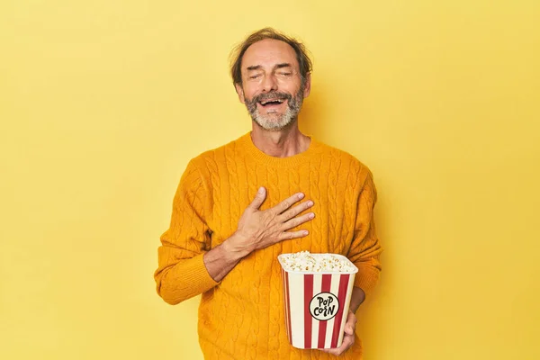 Mężczyzna Korzystający Popcorn Żółtym Studio Śmieje Się Głośno Trzymając Rękę — Zdjęcie stockowe