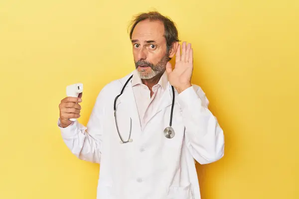 Doctor Holding Infrared Thermometer Studio Trying Listening Gossip — Stock Photo, Image