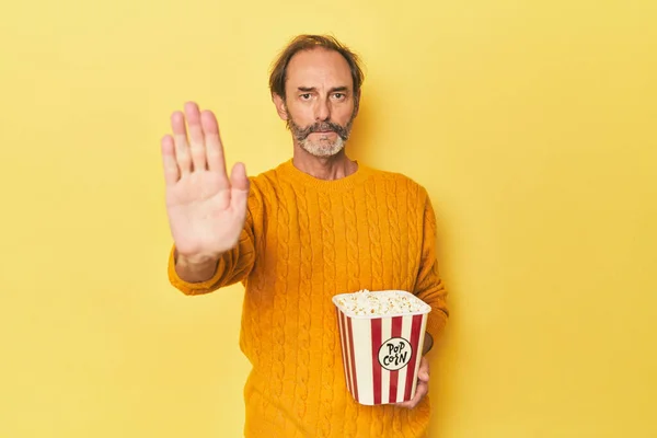 Man Enjoying Popcorn Yellow Studio Standing Outstretched Hand Showing Stop — Stock Photo, Image