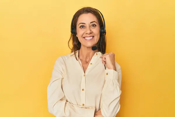 portrait of beautiful adult woman with call center headset on yellow background