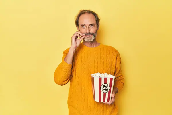 Mann Genießt Popcorn Gelben Studio Mit Fingern Auf Den Lippen — Stockfoto