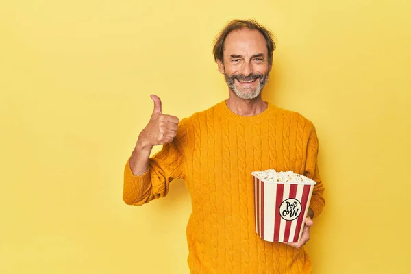 Mężczyzna Korzystających Popcorn Żółtym Studio Uśmiechając Się Podnosząc Kciuk Górę — Zdjęcie stockowe