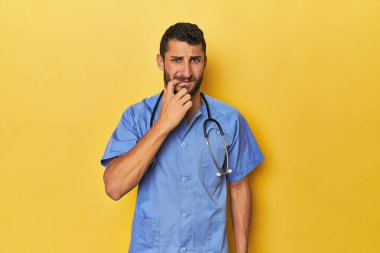 Genç İspanyol erkek hemşire genç İspanyol erkek hemşire kendinden emin bir şekilde tırnaklarını yiyor. Gergin ve endişeli. 