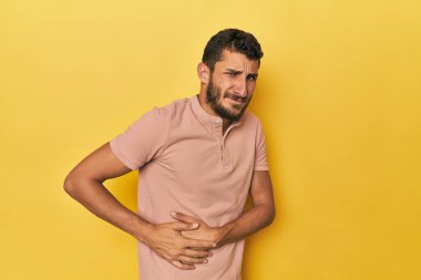 Sarı arka planda, karaciğer ağrısı ve karın ağrısı olan genç bir İspanyol..
