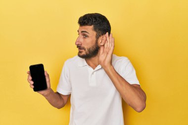 Genç İspanyol bir adam bir dedikoduyu dinlemek için telefon ekranını gösteriyor..